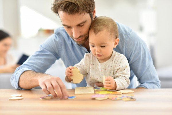 Un père aide son enfant à faire un puzzle