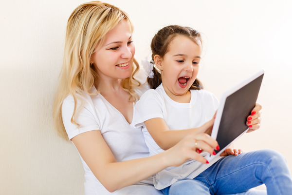 Une mère et une fille rient en jouant sur la tablette.